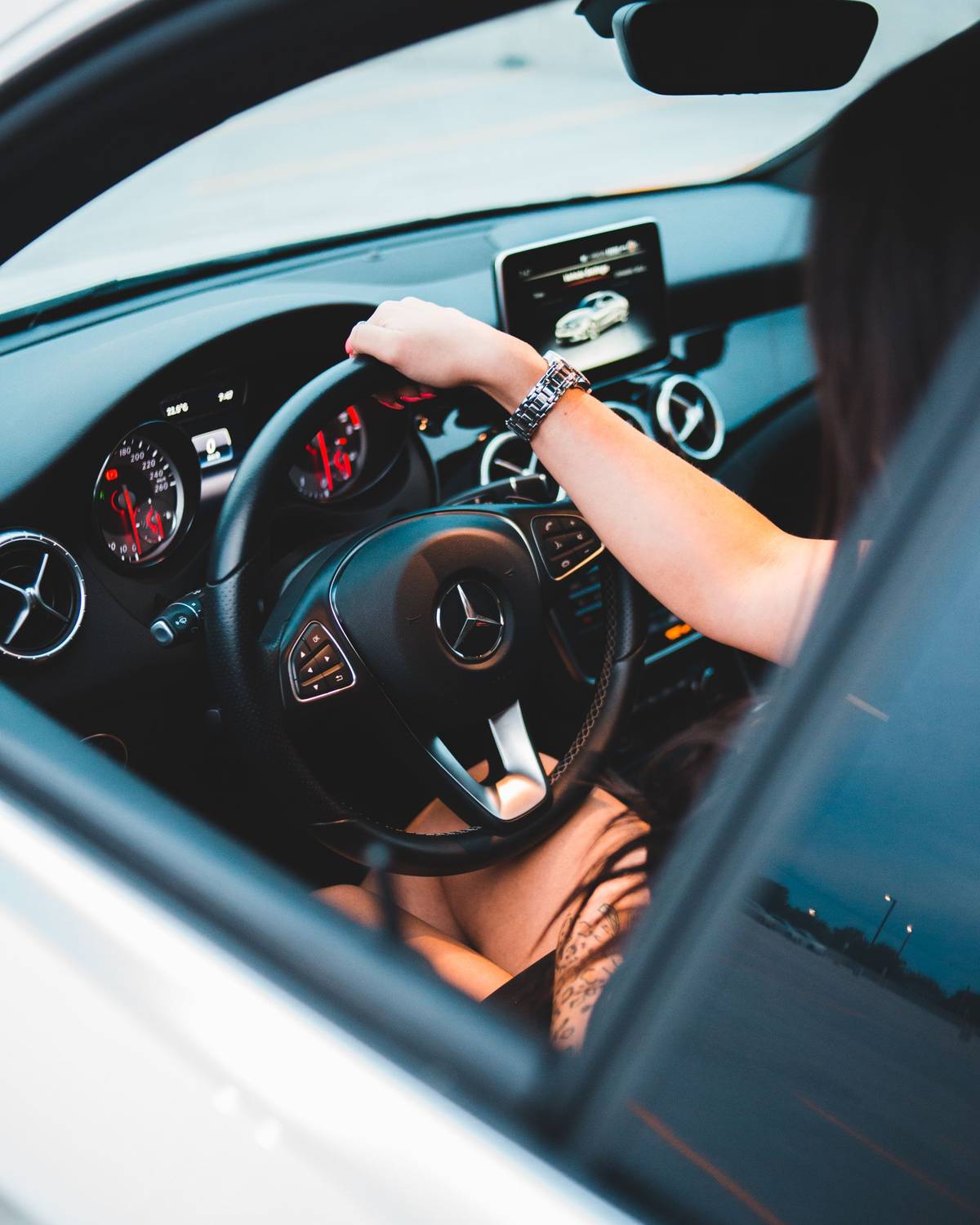 A woman at the wheel of a vehicle, seen from behind.